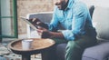 Attractive bearded African businessman using tablet while sitting on sofa at his modern home.Concept of young people Royalty Free Stock Photo