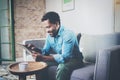 Attractive bearded African businessman using tablet while sitting on sofa at his modern home.Concept of young people Royalty Free Stock Photo