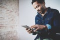 Attractive bearded African man using tablet at his modern home office.Concept of young people working mobile devices Royalty Free Stock Photo