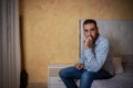 Attractive bearded man depressed and upset in the bedroom. Dramatic 30-40 year old lifestyle portrait, handsome man sitting on bed