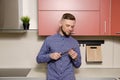 Attractive bearded man examines a knife in his hands in the modern kitchen