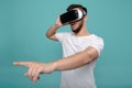 Attractive bearded man trying VR headset and poniting finger. Young man exploring another world with virtual reality