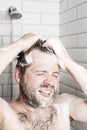 Bearded man washing her hair in the shower under running water.