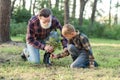 Attractive bearded senior grandfather with his lovely grandson on green lawn planting oak seedling and pour with water. Royalty Free Stock Photo