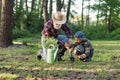 Attractive bearded senior grandfather with his lovely grandson on green lawn planting oak seedling and pour with water. Royalty Free Stock Photo