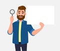 Attractive bearded young man showing/holding magnifying glass and blank/empty poster, paper or sheet in hand. Search, find,