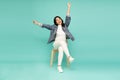 Attractive beautiful Asian woman sitting on white modern chair and hands up raised arms from happiness. Royalty Free Stock Photo