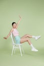 Attractive beautiful Asian woman sitting on white modern chair and hands up raised arms from happiness Royalty Free Stock Photo