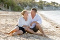 Attractive beautiful couple in love sitting on the beach in romantic summer holidays Royalty Free Stock Photo