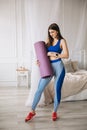 Attractive beautiful sportswoman stands with a gymnastic mat in her hands