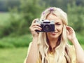 Attractive, young hippie girl taking pictures outdoors at summer. Holiday, vacation, hobby concept. Royalty Free Stock Photo