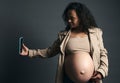 Attractive beautiful young gravid female, expectant mother photographing her tummy in third trimester of happy pregnancy