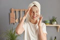 Attractive beautiful young woman posing in kitchen with towel on head wearing white casual t shirt smiling looking away enjoying Royalty Free Stock Photo