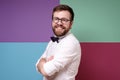 Attractive, benevolent man in glasses, in a shirt and a bow tie, crossed arms and looked at the camera smiling.