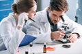 attractive biochemist near coworker looking through Royalty Free Stock Photo