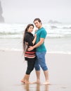 Attractive biracial couple hugging on beach by ocean, foggy day