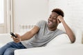 Attractive black african american man sitting at home sofa couch watching television Royalty Free Stock Photo