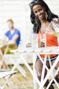 Attractive black woman sitting at a cafe table outdoors and drinking a refreshing beverage