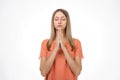 Attractive blond girl prays for wellness of family keeps palms pressed together in praying gesture