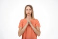 Attractive blond girl prays for wellness of family, keeps palms pressed together in praying gesture