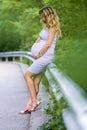 Attractive blond pregnant woman on forest background