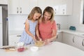 attractive blond 30s woman cooking and baking happy together with sweet adorable mini chef little girl at home modern kitchen Royalty Free Stock Photo