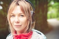 Attractive blond woman in the forest. Close-up portrait of a sporty smiling girl listening to music Royalty Free Stock Photo