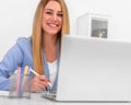 Attractive blonde in a blue business suit in a bright office working on a laptop. Royalty Free Stock Photo
