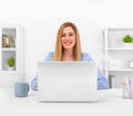 Attractive blonde in a blue business suit in a bright office working on a laptop. Royalty Free Stock Photo