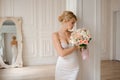 Attractive blonde bride in the elegant white dress holding a wedding bouquet Royalty Free Stock Photo