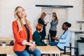 Attractive blonde business woman in red jacket smiling at camera with colleagues working in background Royalty Free Stock Photo