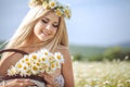 Attractive blonde in chamomile field. Young woman in wreath