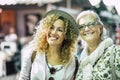 Attractive blonde curly haired woman with a senior friend smile enjoying being together at the flea market. Friendship and Royalty Free Stock Photo