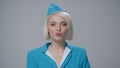 An attractive blonde flight attendant chews chewing gum and smiles a snow-white smile.