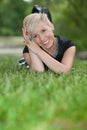 Attractive blonde girl posing in nature lying on grass