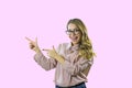 Attractive blonde girl in shirt and glasses stands sideways with a smile and points fingers at copyspace on an isolated Royalty Free Stock Photo
