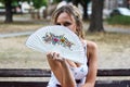 Attractive Blonde Girl Sitting on the Bench in a Park and Hiding Royalty Free Stock Photo