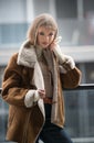 Attractive blonde model with pantyhose, black bra and fur coat posing provocatively on chair. Royalty Free Stock Photo