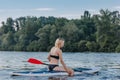 attractive blonde sportswoman sitting on paddle board