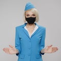 Attractive blonde stewardess in protective mask holds safety instructions