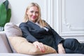 Attractive blonde woman in a business gray suit is sitting on the couch