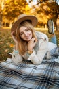 Attractive blonde woman in coat and hat is drinking tea at a picnic in an autumn park. Autumn concept. Royalty Free Stock Photo