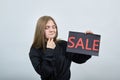 Attractive blonde woman, keeping adverising sale, keeping hand on chin, thinking Royalty Free Stock Photo
