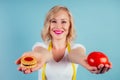 Attractive blonde woman with make-up and lips color fuchsia makes a choice between high-calorie cookie biscuit and Royalty Free Stock Photo