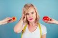 Attractive blonde woman with make-up and lips color fuchsia makes a choice between high-calorie cookie biscuit and Royalty Free Stock Photo