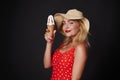 Attractive blonde woman in red swimsuit with white polka dots, holding delicious ice cream cone , smiling beautiful toothy smile, Royalty Free Stock Photo