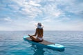 Blonde woman relaxes in a yoga position on a stand up paddle board SUP Royalty Free Stock Photo