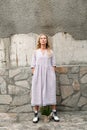 Attractive woman standing near stone wall outdoors with plant near her feet Royalty Free Stock Photo