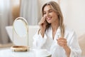 Attractive blonde woman using face tonner, looking at mirror Royalty Free Stock Photo