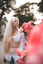 Attractive blonde woman 25 - 29 year old holding pink rose flowers in park outdoors. Healthy natural skin. Spring season. Royalty Free Stock Photo